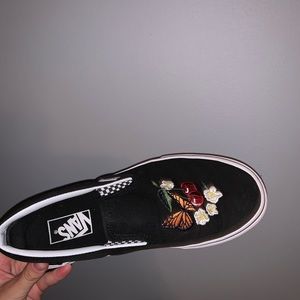 Embroidered black canvas slip-on vans.